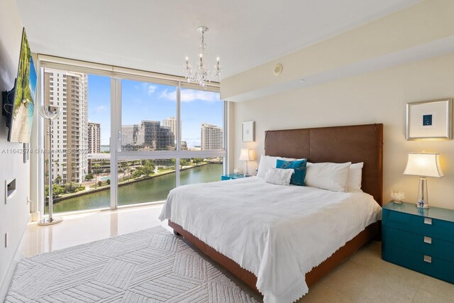 tiled bedroom featuring a water view, multiple windows, a wall of windows, and a chandelier