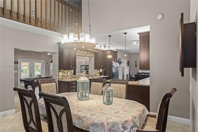 tiled dining space featuring sink, french doors, and a high ceiling