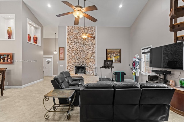 tiled living room featuring ceiling fan, high vaulted ceiling, and a stone fireplace