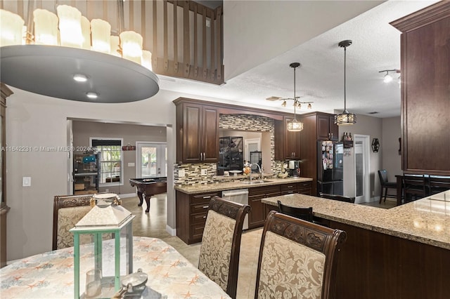 kitchen featuring dark brown cabinetry, light stone counters, pool table, a textured ceiling, and hanging light fixtures