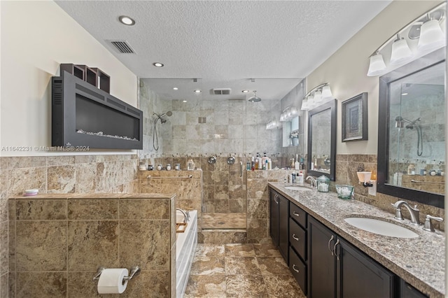 bathroom with tile patterned flooring, tile walls, double vanity, and a textured ceiling