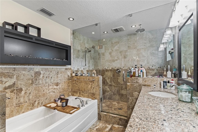 bathroom with separate shower and tub, tile walls, a textured ceiling, vanity, and tile patterned flooring