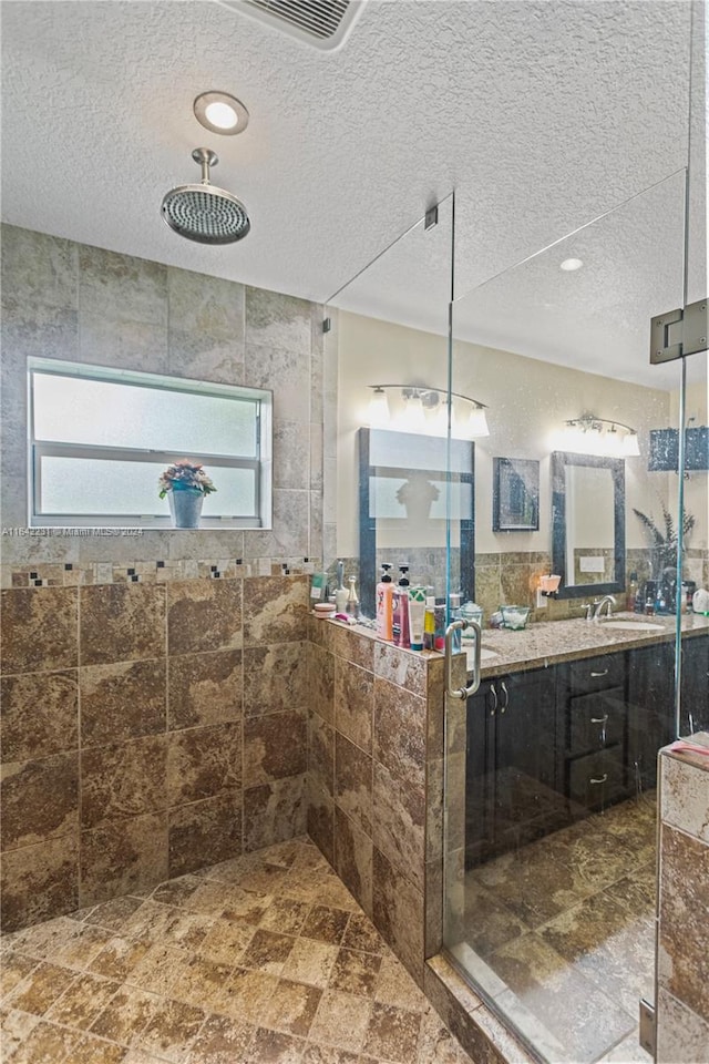 bathroom featuring tiled shower, tile patterned floors, a textured ceiling, and vanity