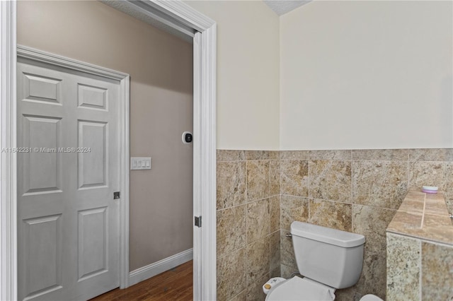 bathroom featuring tile walls, hardwood / wood-style floors, and toilet