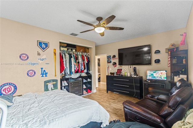 bedroom with ceiling fan, a closet, a textured ceiling, and light hardwood / wood-style floors