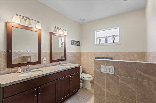 bathroom with tile walls, double sink vanity, tile patterned floors, and a bathtub