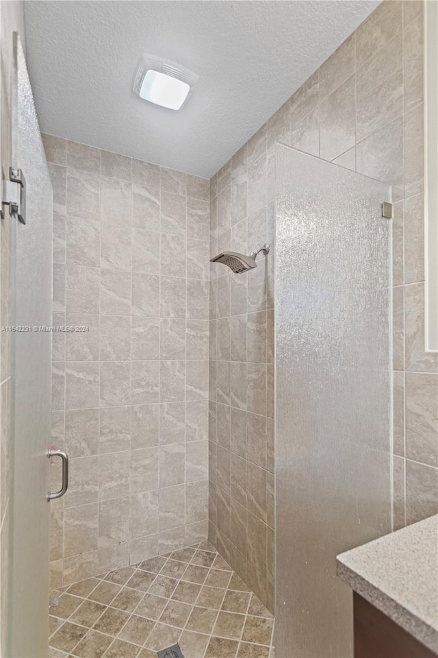 bathroom featuring a textured ceiling and a shower with door