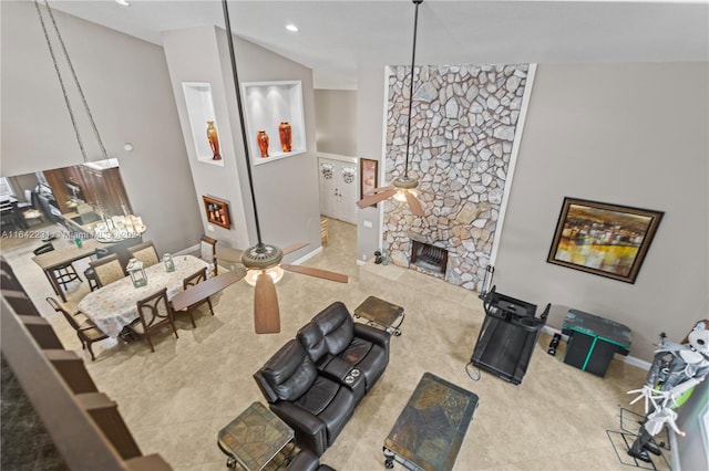 living room featuring ceiling fan, high vaulted ceiling, light tile patterned flooring, and a stone fireplace