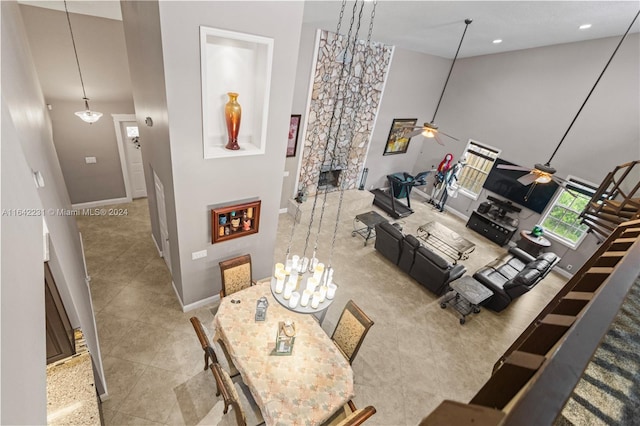 living room with ceiling fan, a towering ceiling, and tile patterned floors