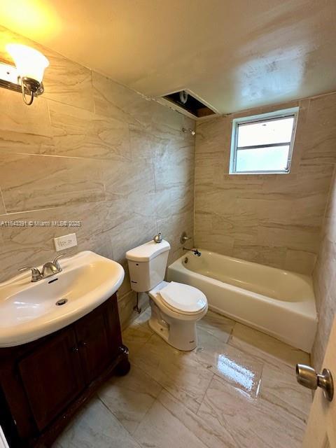 full bathroom with toilet, tiled shower / bath combo, tile walls, and vanity