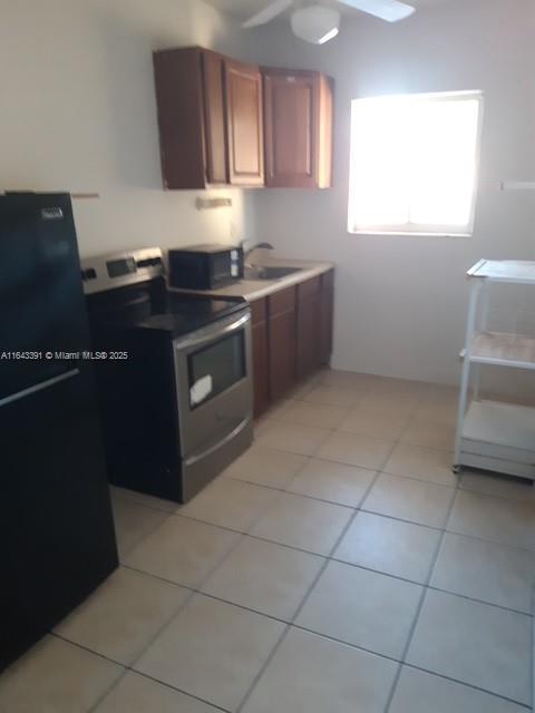 kitchen featuring light tile patterned flooring, black appliances, and sink