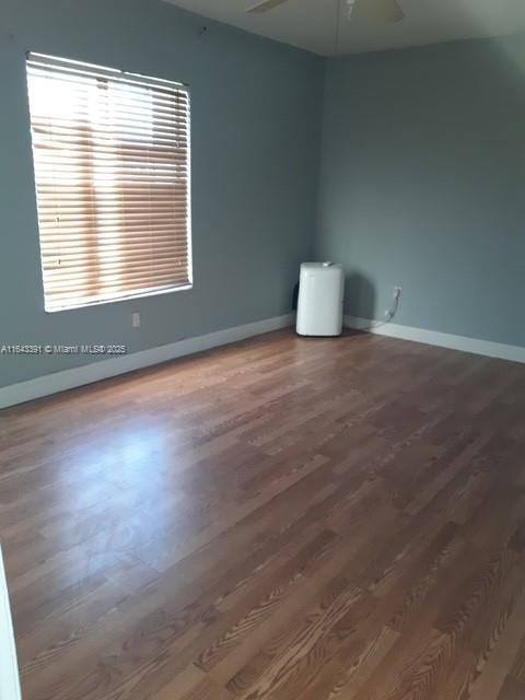 unfurnished room featuring ceiling fan and dark wood-type flooring