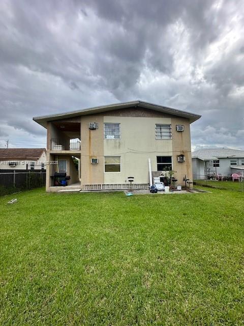 back of house featuring a balcony and a yard