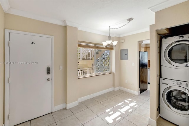 washroom with light tile patterned flooring, an inviting chandelier, stacked washer and dryer, ornamental molding, and electric panel