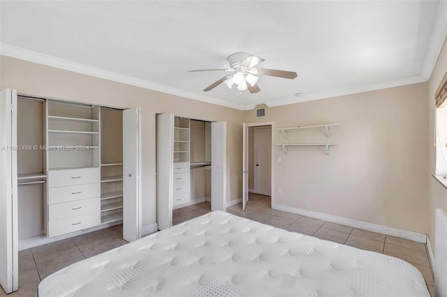 tiled bedroom with ceiling fan, multiple closets, and ornamental molding