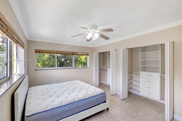 bedroom featuring ceiling fan, two closets, and ornamental molding