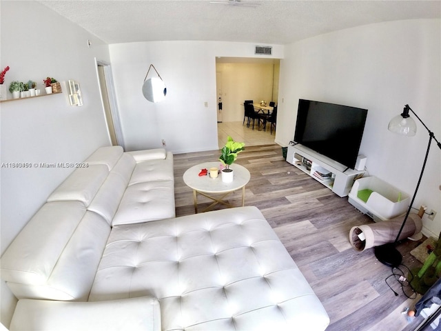 living room featuring wood finished floors, visible vents, and a textured ceiling