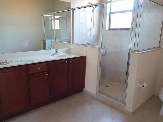 bathroom featuring tile patterned flooring, vanity, a shower with door, and toilet