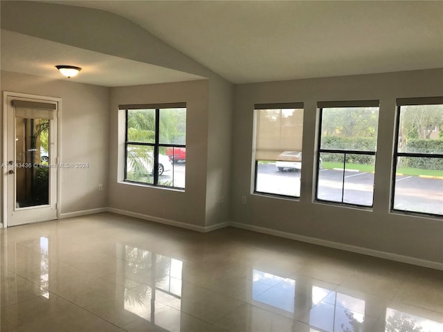 empty room featuring vaulted ceiling and light tile patterned floors