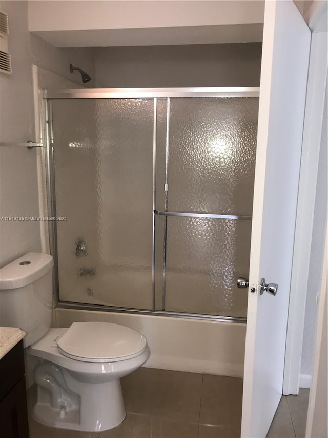 full bathroom featuring tile patterned flooring, toilet, vanity, and bath / shower combo with glass door