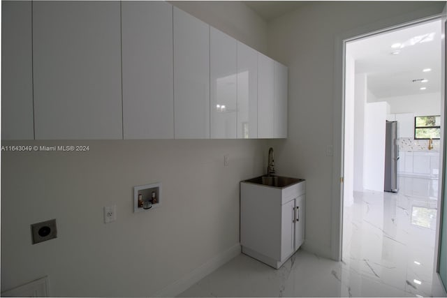 clothes washing area with sink, washer hookup, cabinets, electric dryer hookup, and light tile patterned floors