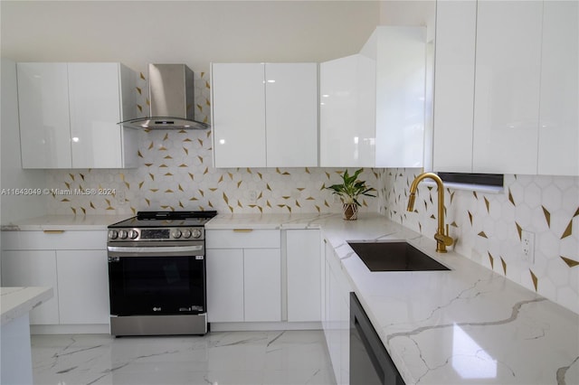 kitchen with wall chimney range hood, decorative backsplash, white cabinetry, light stone countertops, and stainless steel range