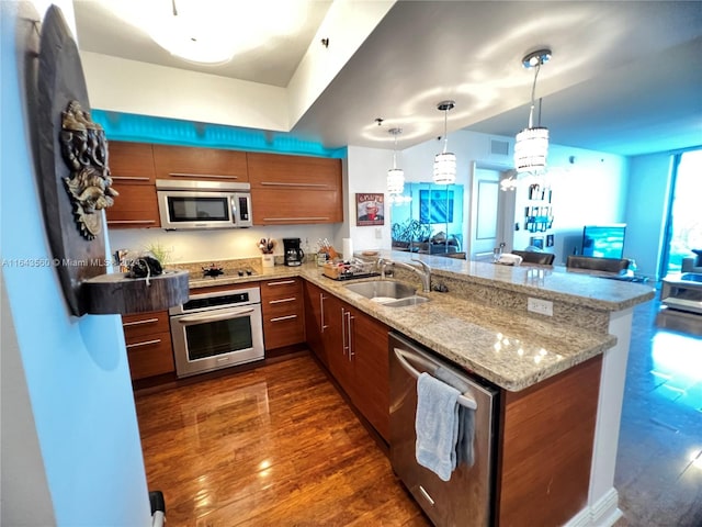 kitchen featuring hanging light fixtures, sink, kitchen peninsula, appliances with stainless steel finishes, and dark hardwood / wood-style flooring