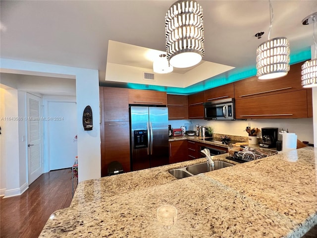 kitchen with pendant lighting, dark hardwood / wood-style floors, kitchen peninsula, appliances with stainless steel finishes, and light stone countertops