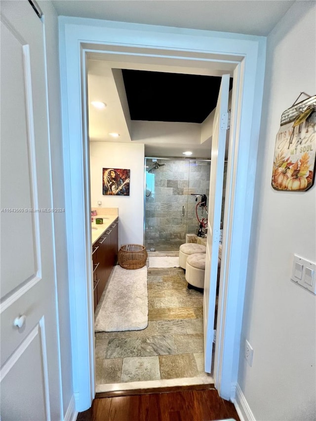 bathroom featuring wood-type flooring, a shower with door, and vanity