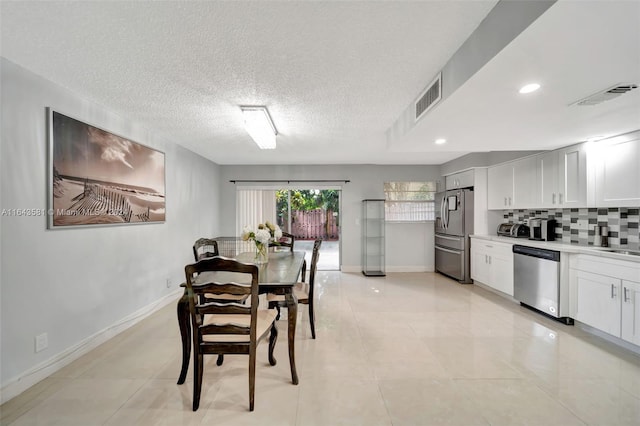 dining space with a textured ceiling and light tile patterned floors