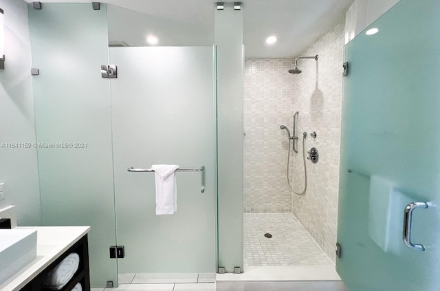 bathroom with tile patterned floors, a tile shower, and vanity