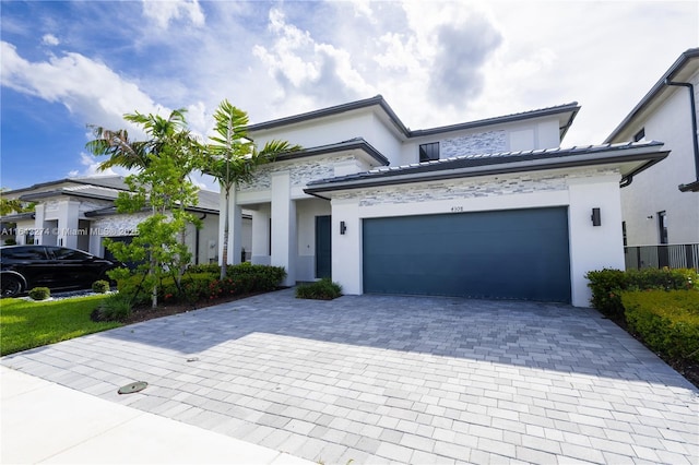 view of front of property featuring an attached garage, decorative driveway, and stucco siding