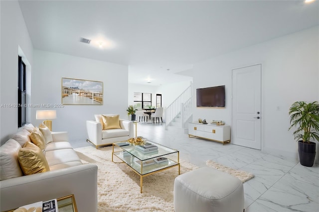 living room featuring marble finish floor, stairway, and visible vents