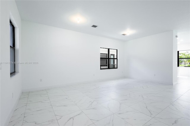 spare room featuring marble finish floor, visible vents, and baseboards