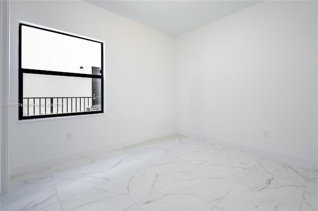 unfurnished room featuring marble finish floor and baseboards