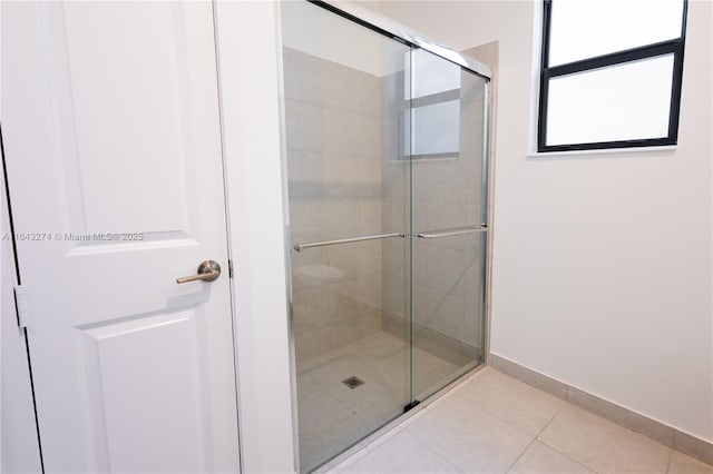 bathroom with a stall shower, baseboards, and tile patterned floors