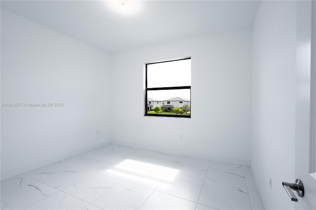 unfurnished room featuring marble finish floor and baseboards