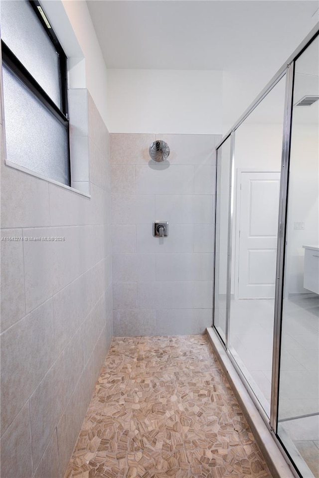 bathroom with a stall shower and visible vents