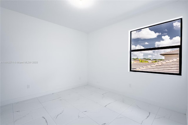 empty room featuring marble finish floor and baseboards