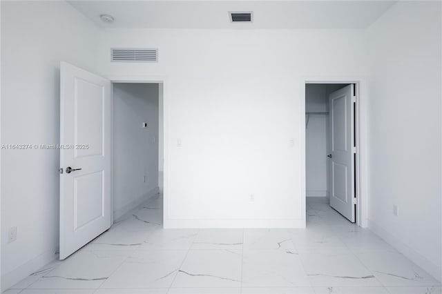 empty room with marble finish floor, visible vents, and baseboards