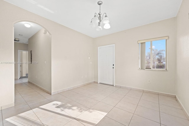 tiled empty room with a notable chandelier