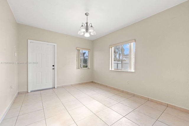 tiled spare room featuring a chandelier