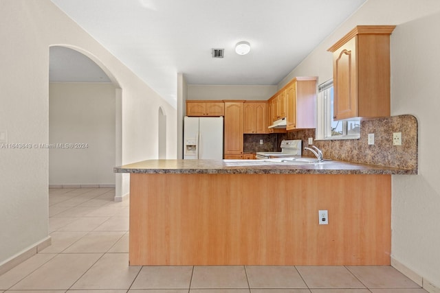 kitchen with kitchen peninsula, light brown cabinetry, decorative backsplash, white appliances, and light tile patterned flooring