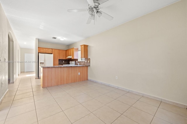 kitchen with kitchen peninsula, backsplash, ceiling fan, white refrigerator with ice dispenser, and light tile patterned flooring