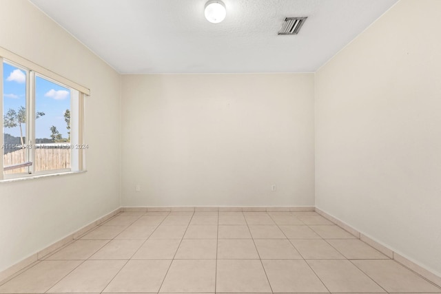 empty room with light tile patterned floors and a textured ceiling