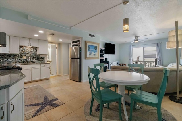 dining area featuring light tile patterned floors, sink, ceiling fan, and a textured ceiling