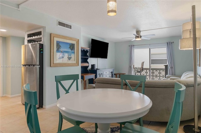 tiled dining area with ceiling fan and a textured ceiling