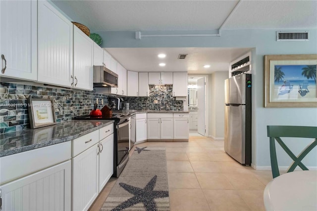 kitchen featuring tasteful backsplash, white cabinetry, light tile patterned floors, dark stone countertops, and stainless steel appliances