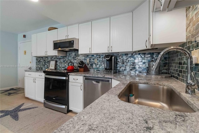 kitchen with light stone counters, tasteful backsplash, appliances with stainless steel finishes, white cabinetry, and a sink