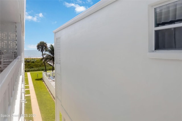 view of side of home with a water view, a yard, a balcony, and stucco siding